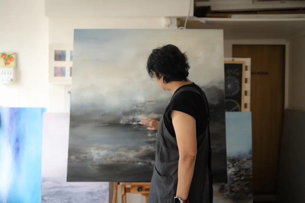 The artist working close to the canvas, hand to the surface